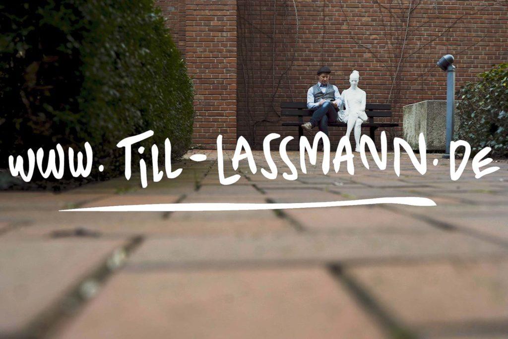 Eventzeicher Till Lassmann sitzt auf einer Parkbank neben einer Frauen Statue