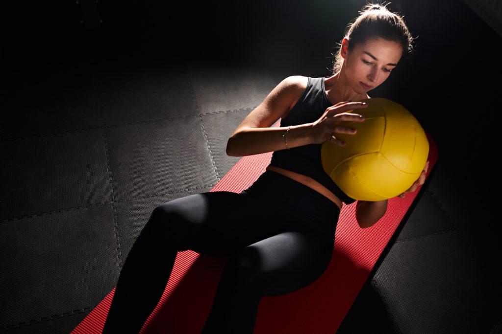 Frau macht Sport mit Ball auf einer rote matte